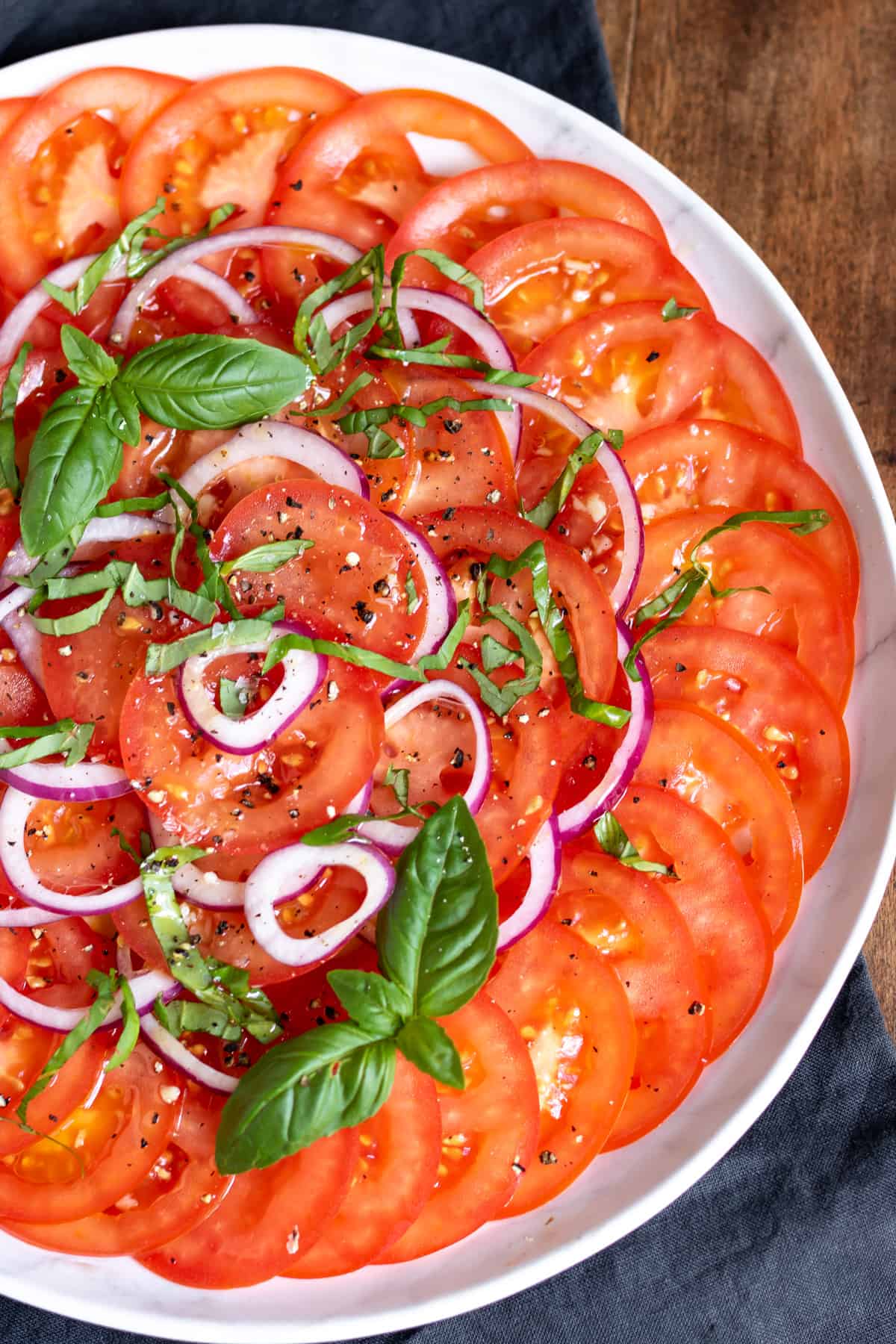 Close up of a salad with sliced tomatoes and onion.