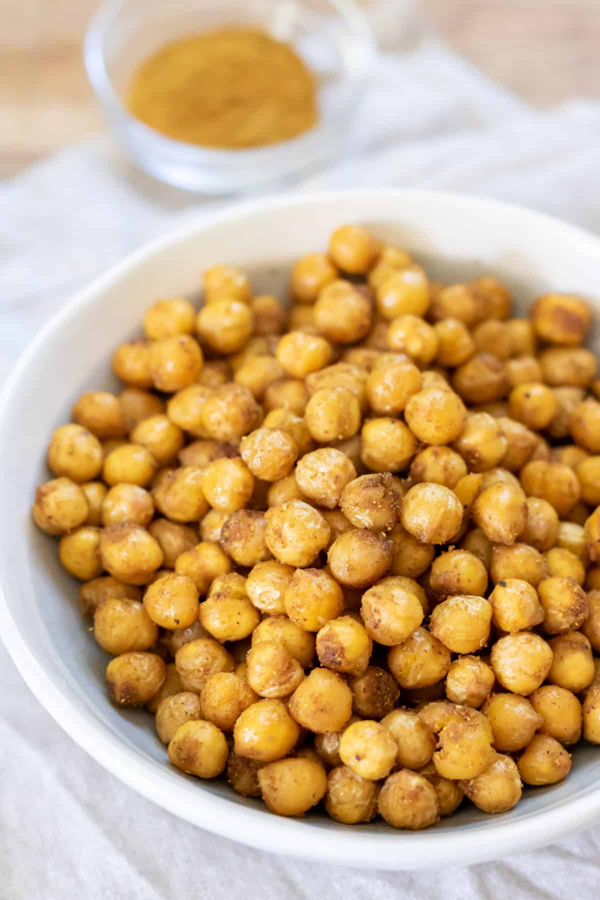 Table with a bowl of air fried chickpeas next to a dish of spices.