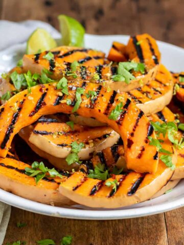 Wooden table with a plate of grilled butternut squash.