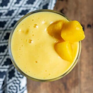 Looking down at a glass of smoothie with mango chunks to garnish.