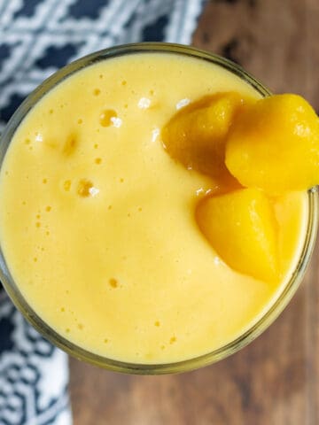 Looking down at a glass of smoothie with mango chunks to garnish.