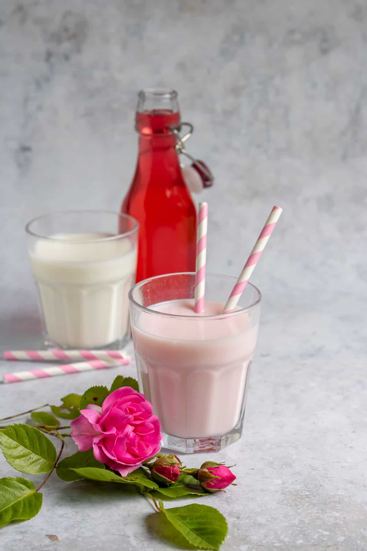 Glass of rose milk with striped straws.