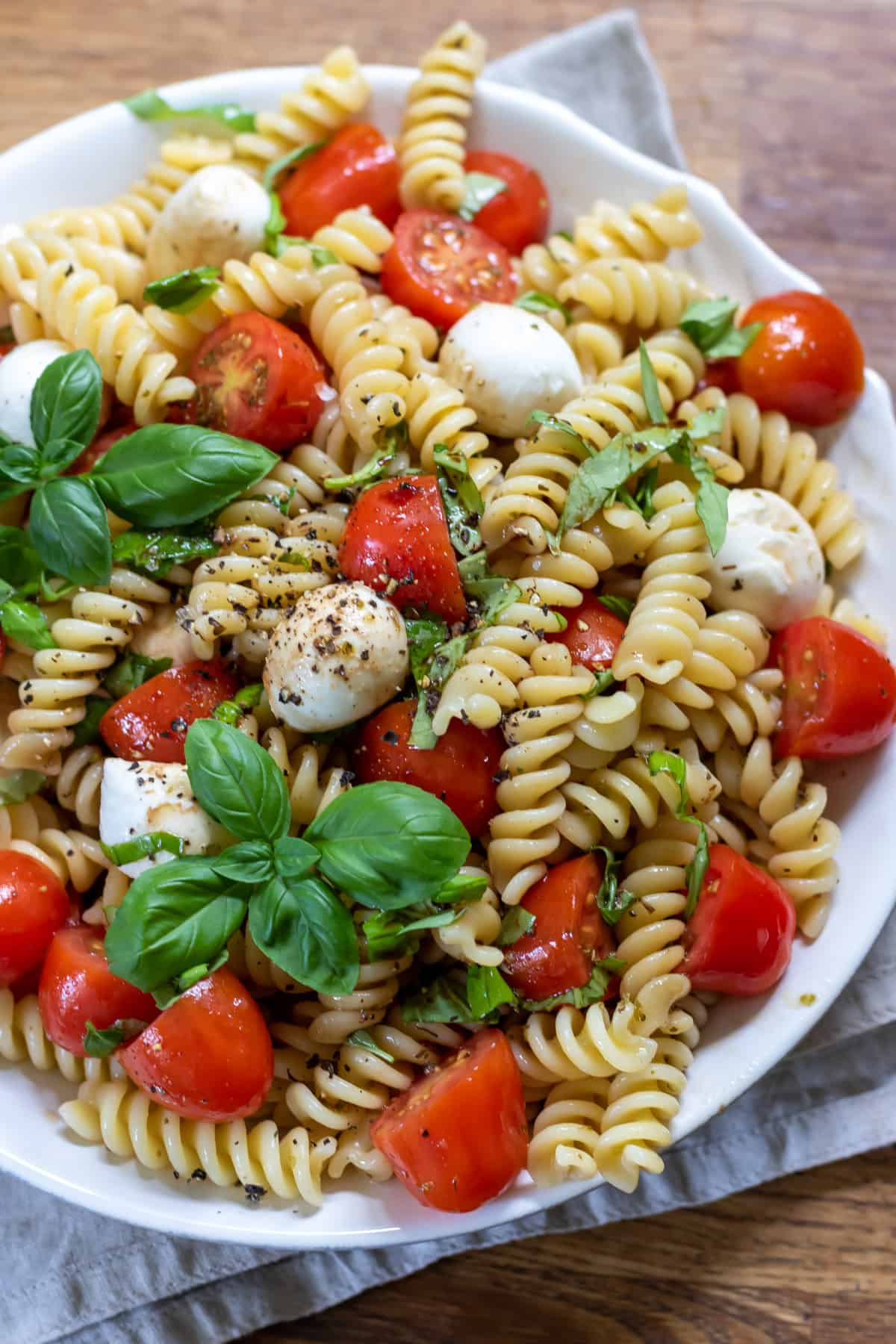 Close up of a plate of caprese pasta salad on a tabe.