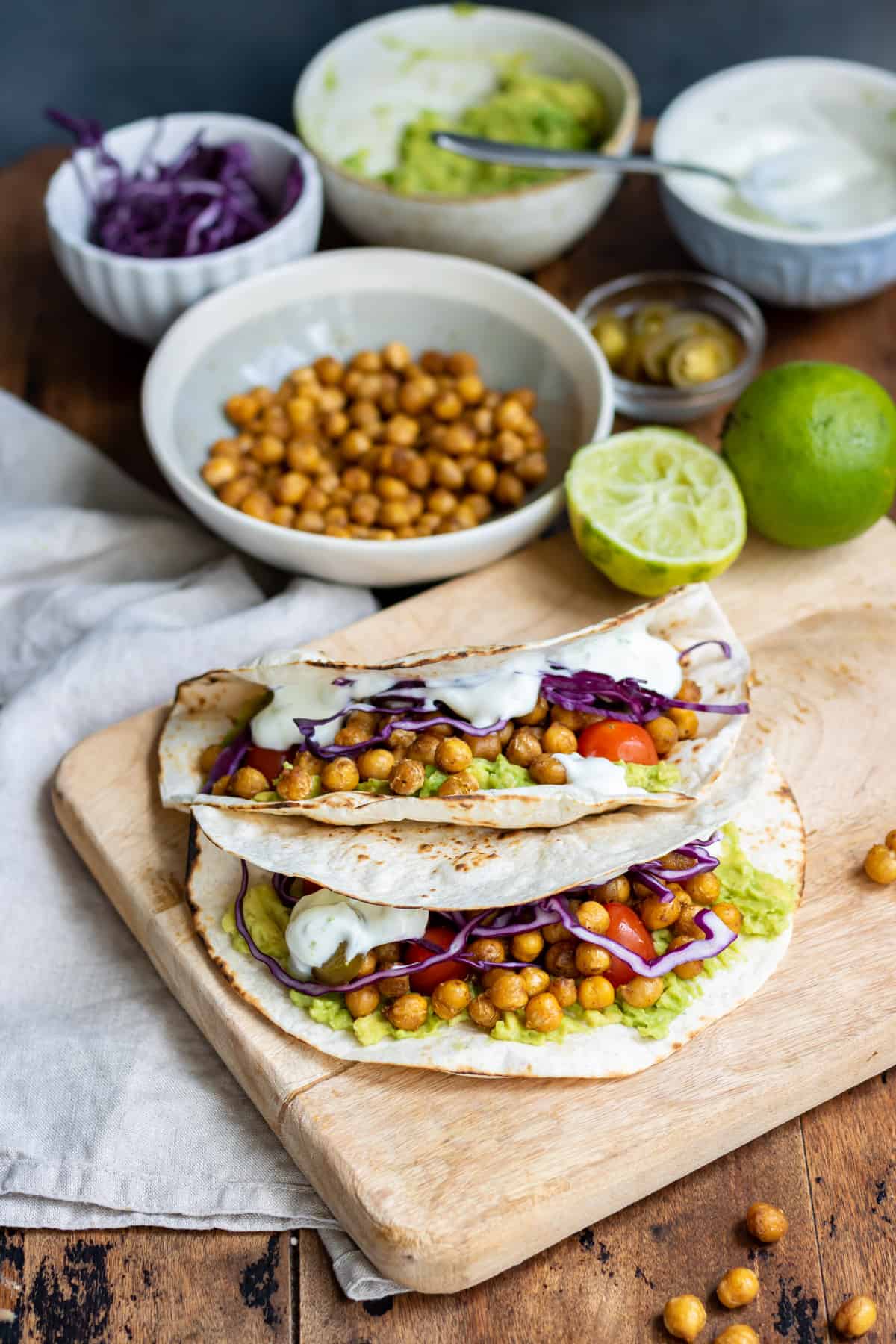 Chickpea tacos on a wooden board in front of ingredients.