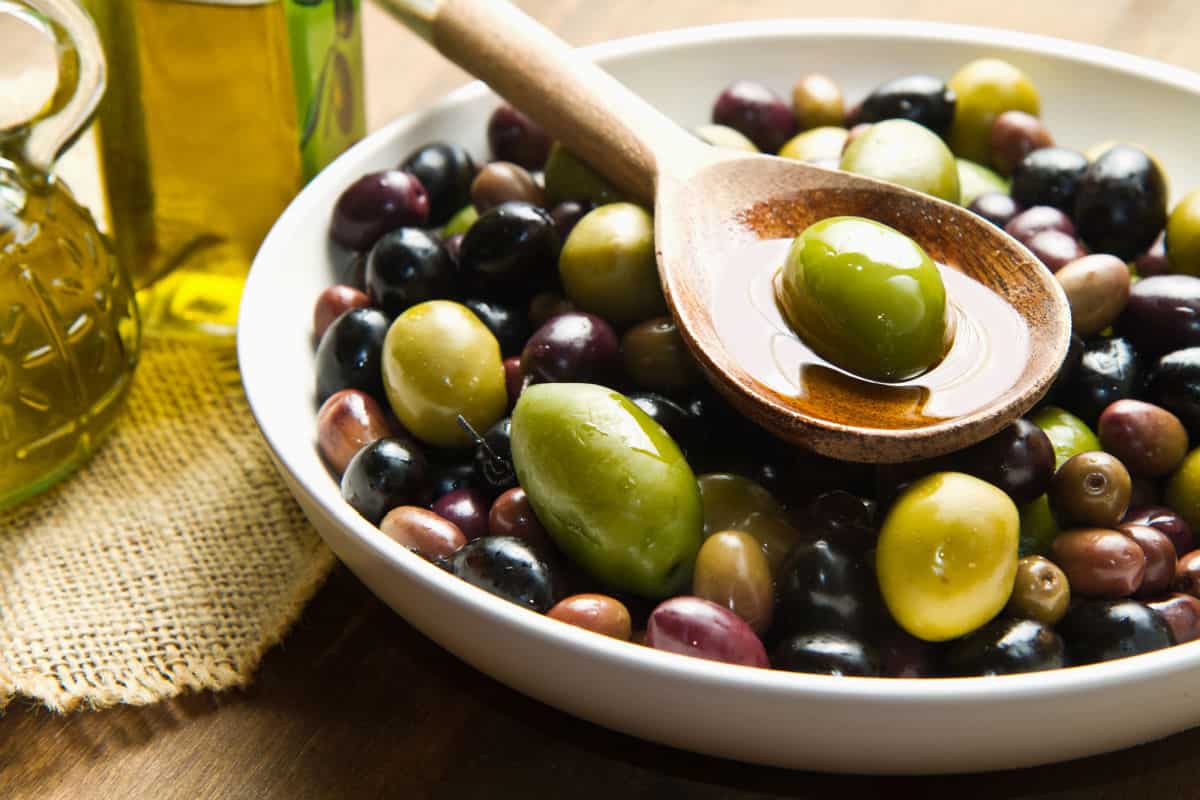 Dish of olives with a wooden spoon.