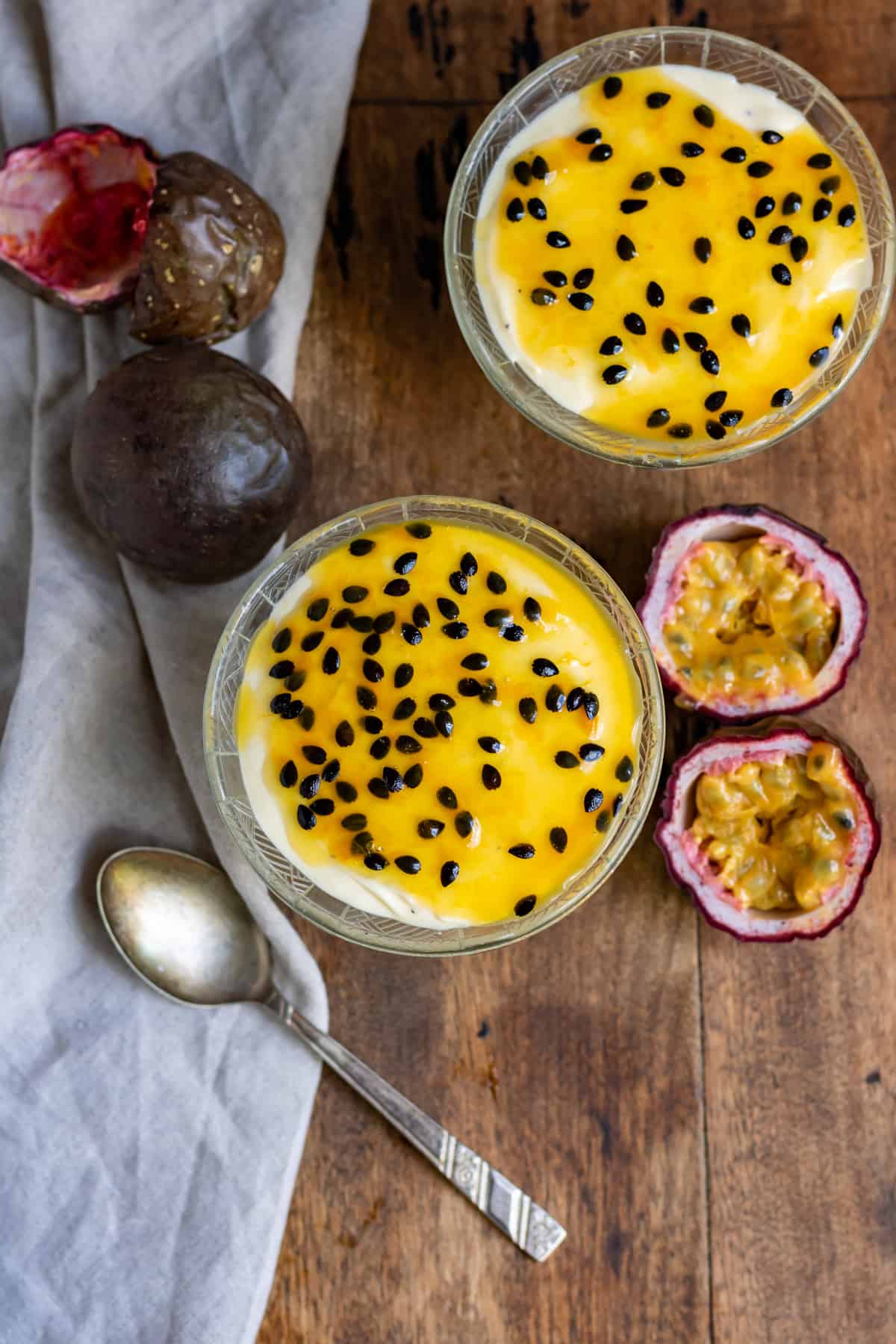 Wooden table with two glass dishes of passion fruit mousse.