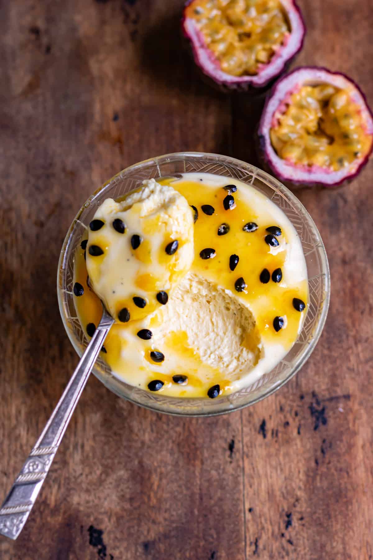 Spoonful resting on a dish of mousse topped with passion fruit pulp.