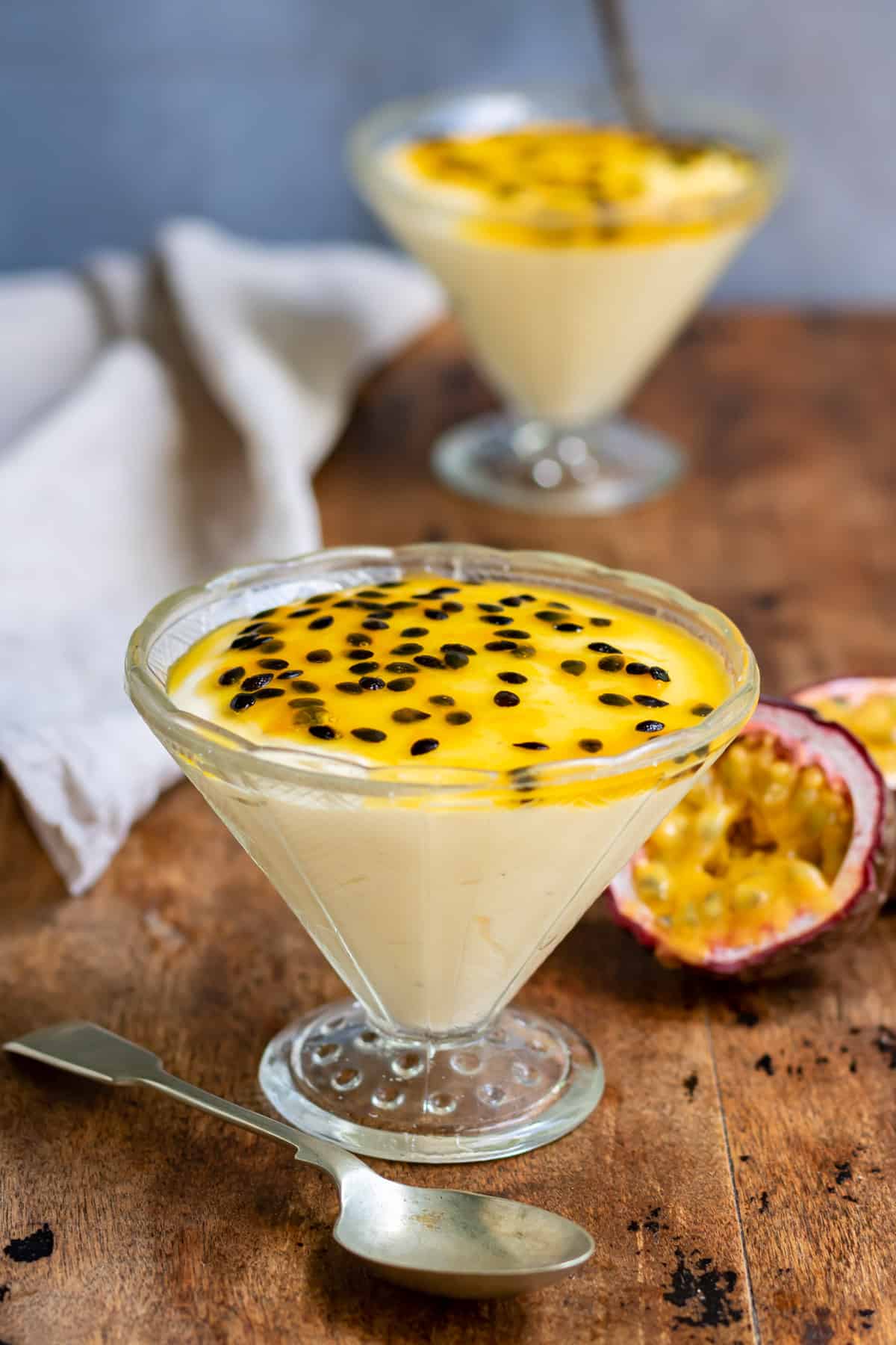 Table with dishes of mousse next to cut open passion fruits.