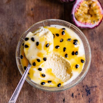 Spoonful resting on a glass dish of passionfruit mousse.