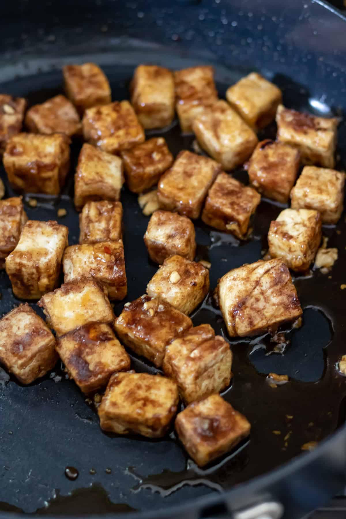 Tossing fried tofu in sticky sauce.