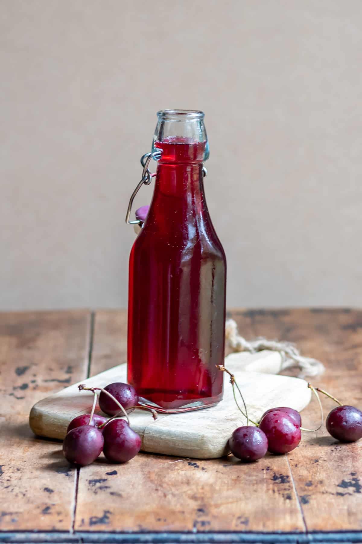 Bottle of cherry simple syrup on a wooden table.