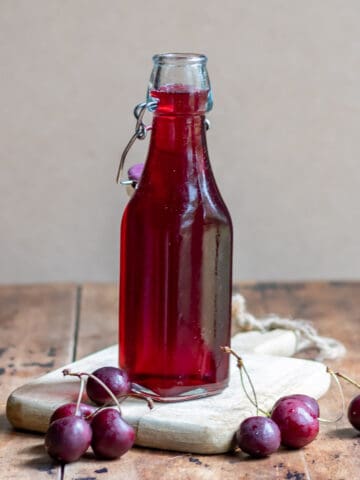 Bottle of cherry simple syrup on a wooden table.