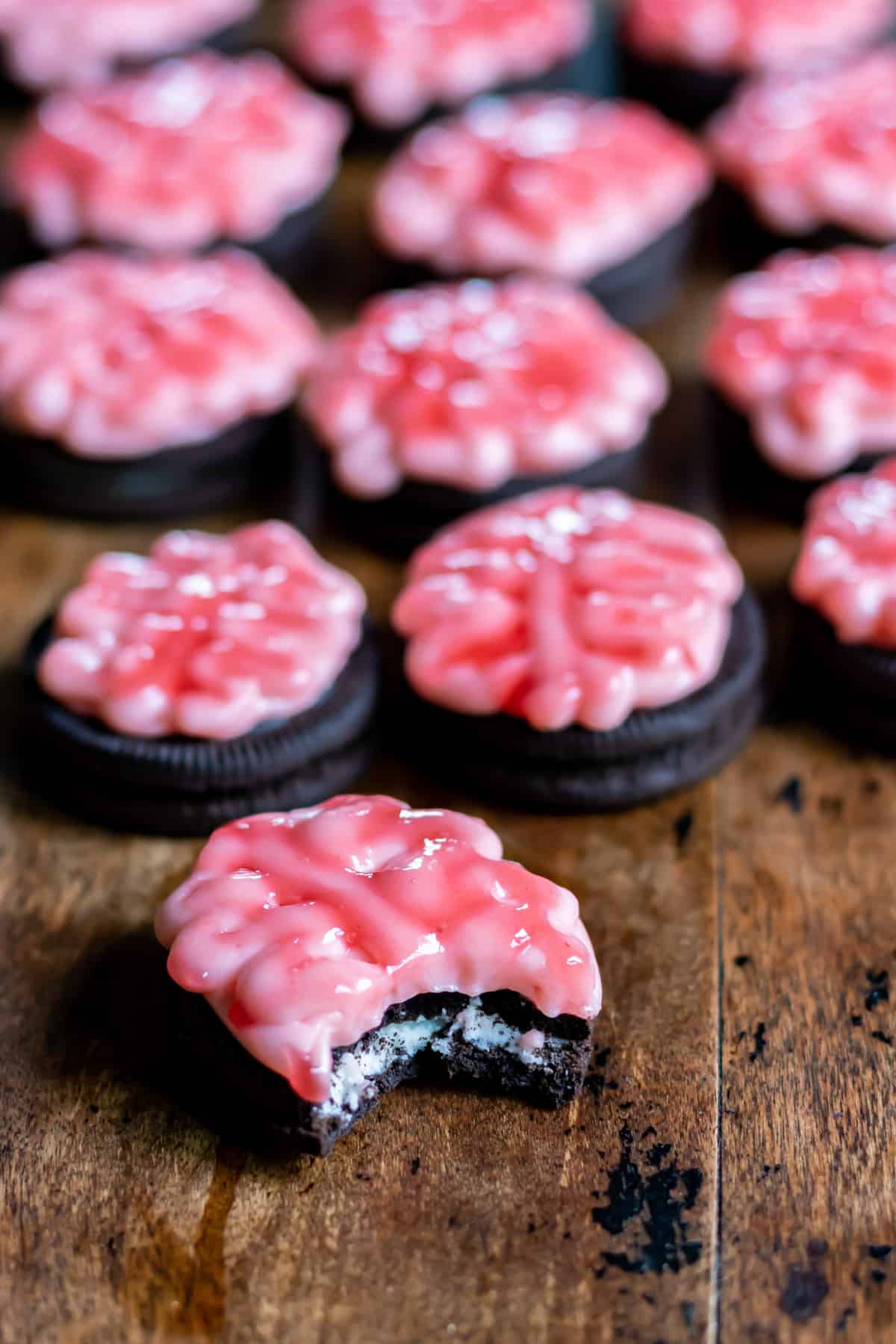 Cookie with a bite out in front of rows of Oreo cookies decorated like brains for Halloween.