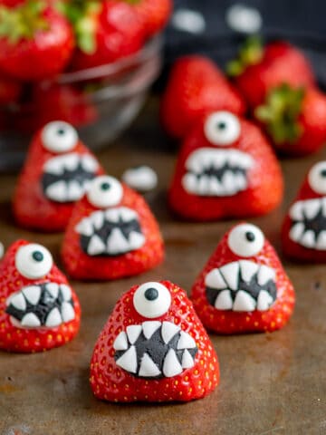Rows of strawberries decorated with fondant mouths and candy eyes.