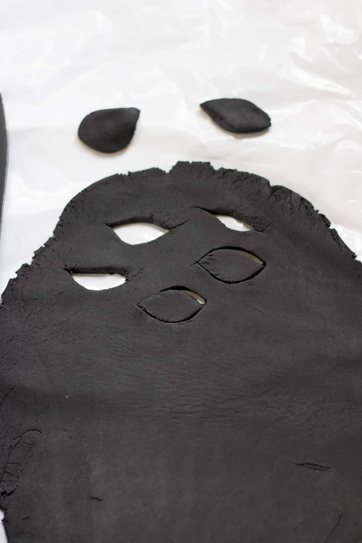 Cutting oval mouths out of black fondant icing.