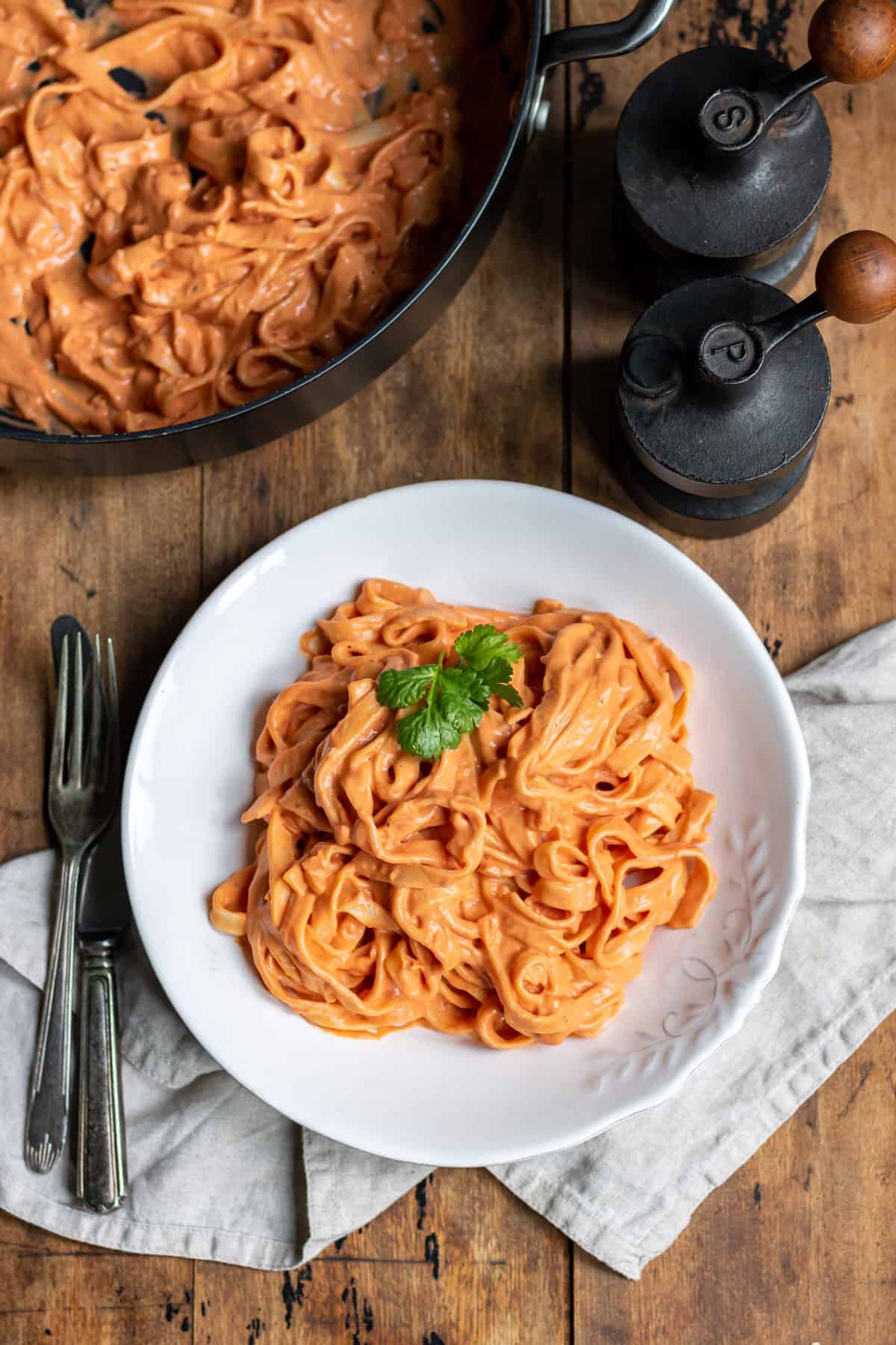 Wooden table with a plate of pink sauce pasta.