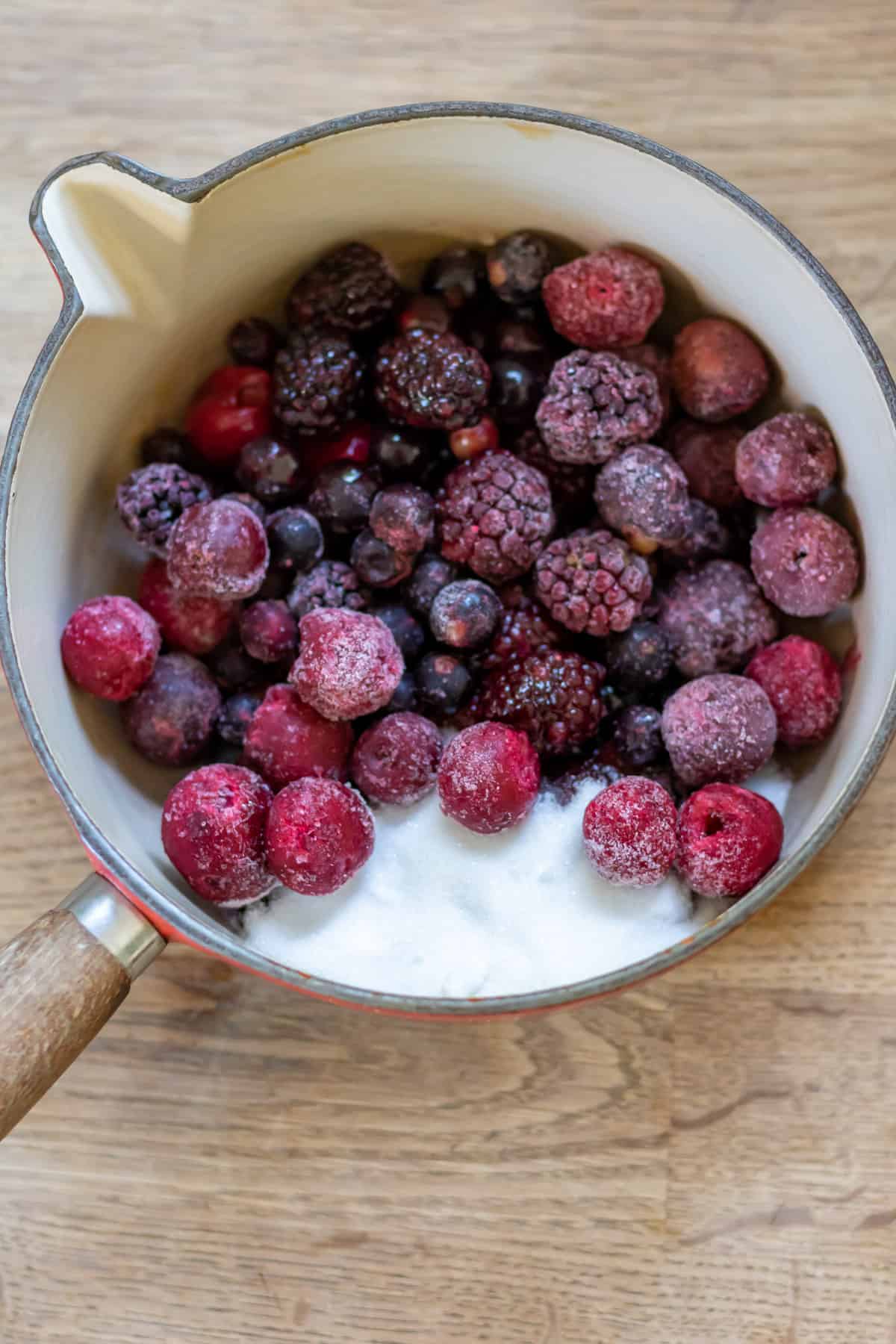 Frozen berries and sugar in a pot.