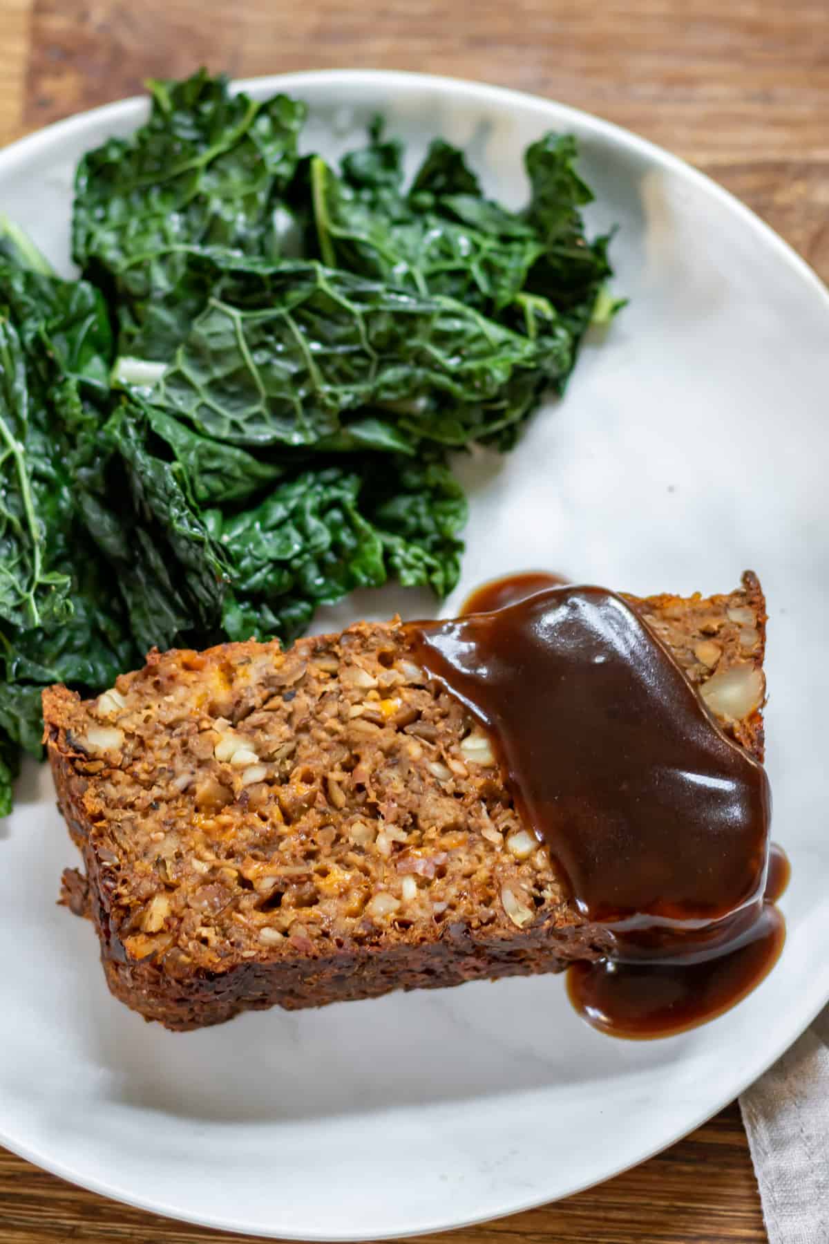 Slice of nut roast on a plate with vegetables and gravy.