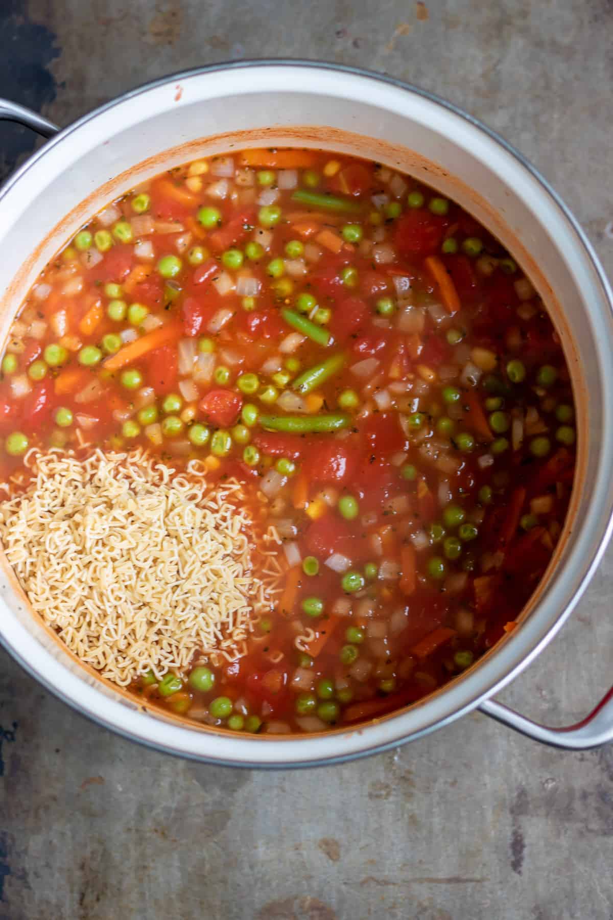 Adding alphabet pasta to the soup base.