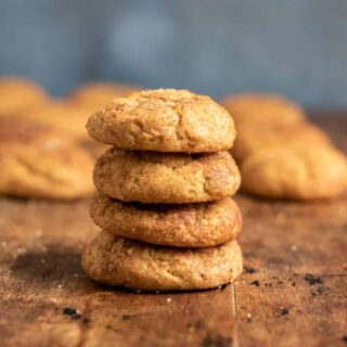 Wooden table with pumpkin snickerdoodles in a stack.