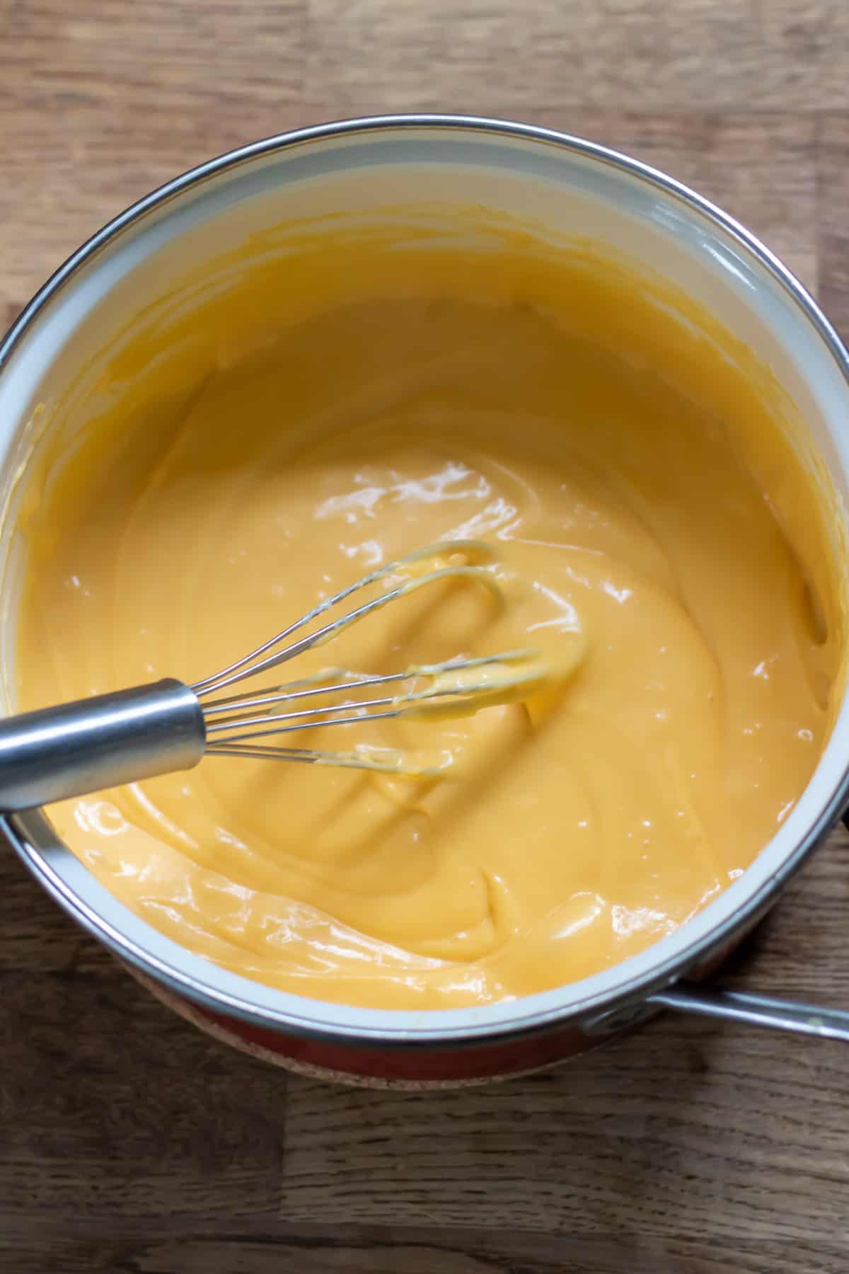 Whisking the finished cheese sauce in a pot.