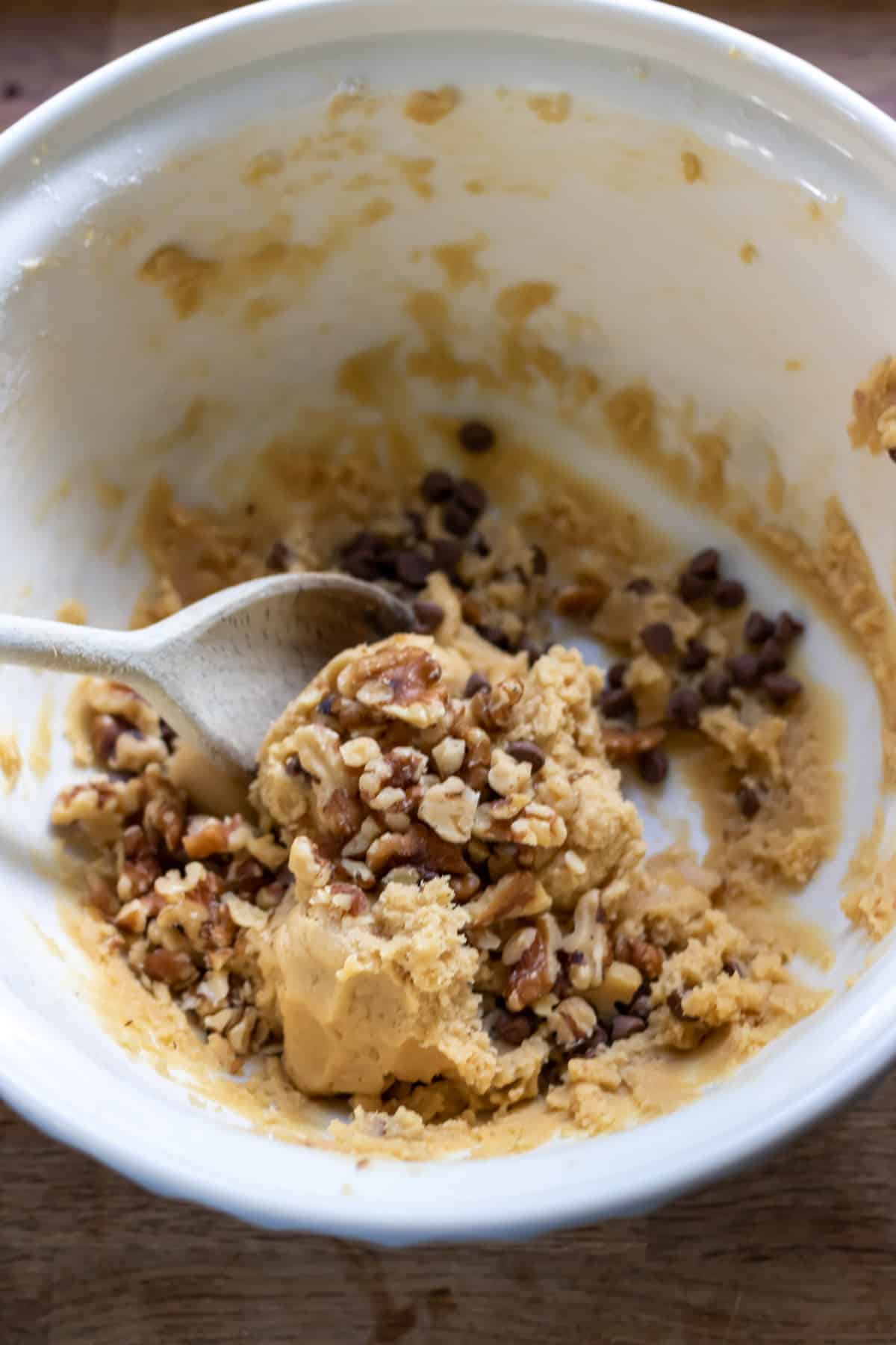 Stirring walnuts and chocolate chips into cookie dough.