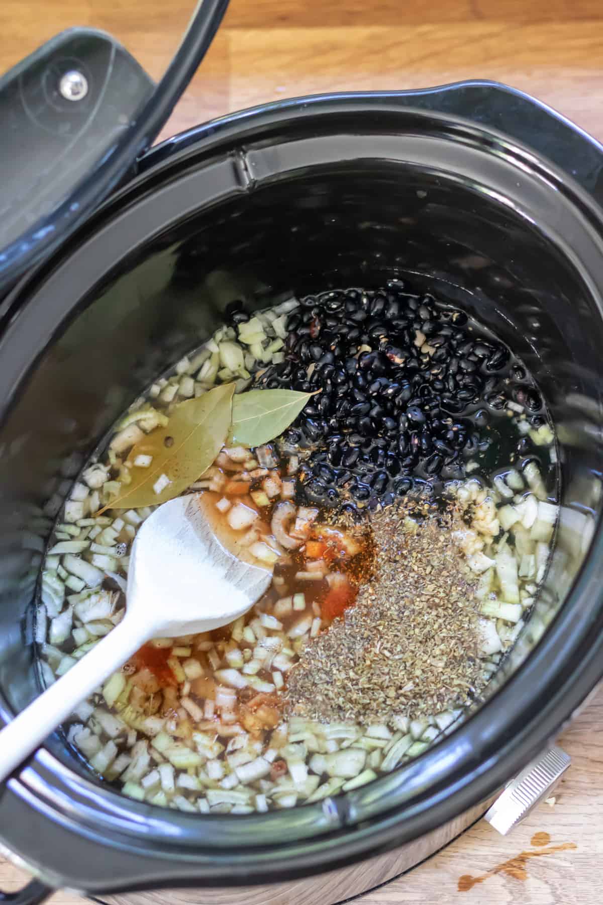 Stirring ingredients in a slow cooker bowl.