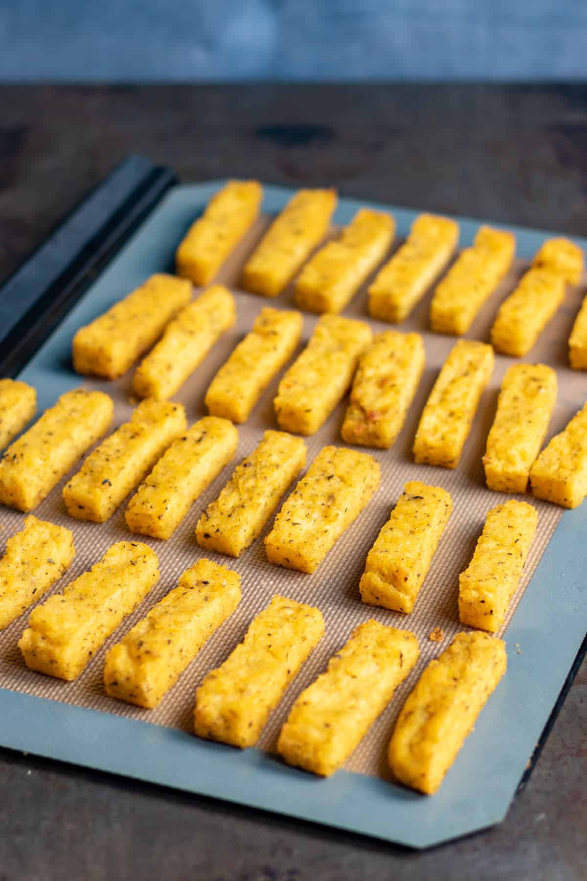 Rows of baked polenta fries on a baking sheet.