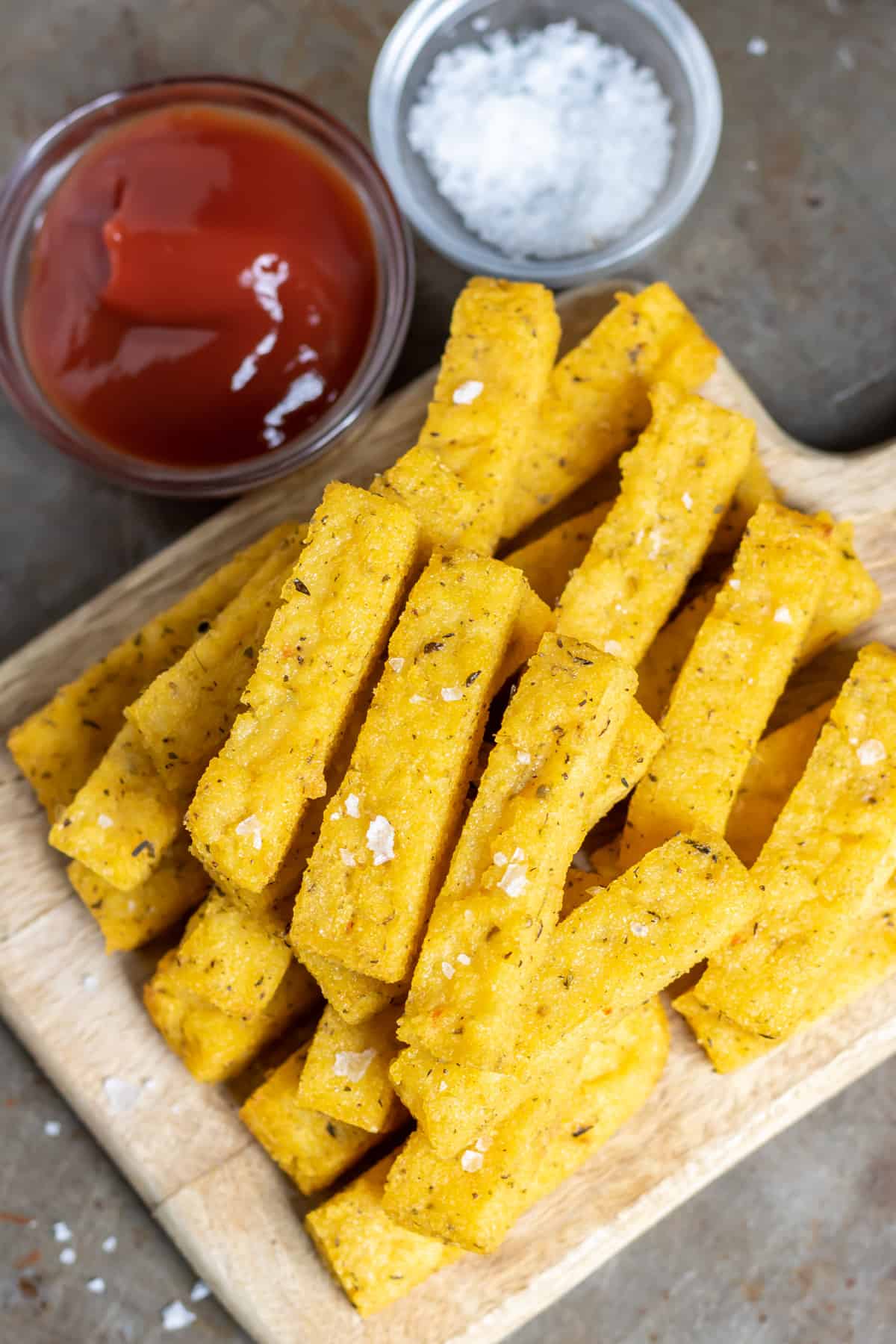 Looking down at polenta fries stacked on a wooden board.