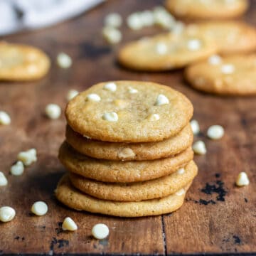 Stack of cookies surrounded by white chocolate chips.