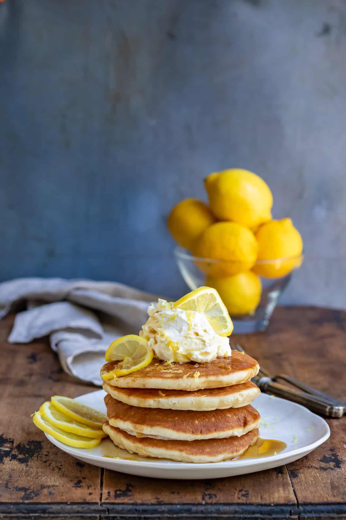 Table with a plate stacked with lemon pancakes.
