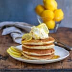 Wooden table with a plate of lemon pancakes.