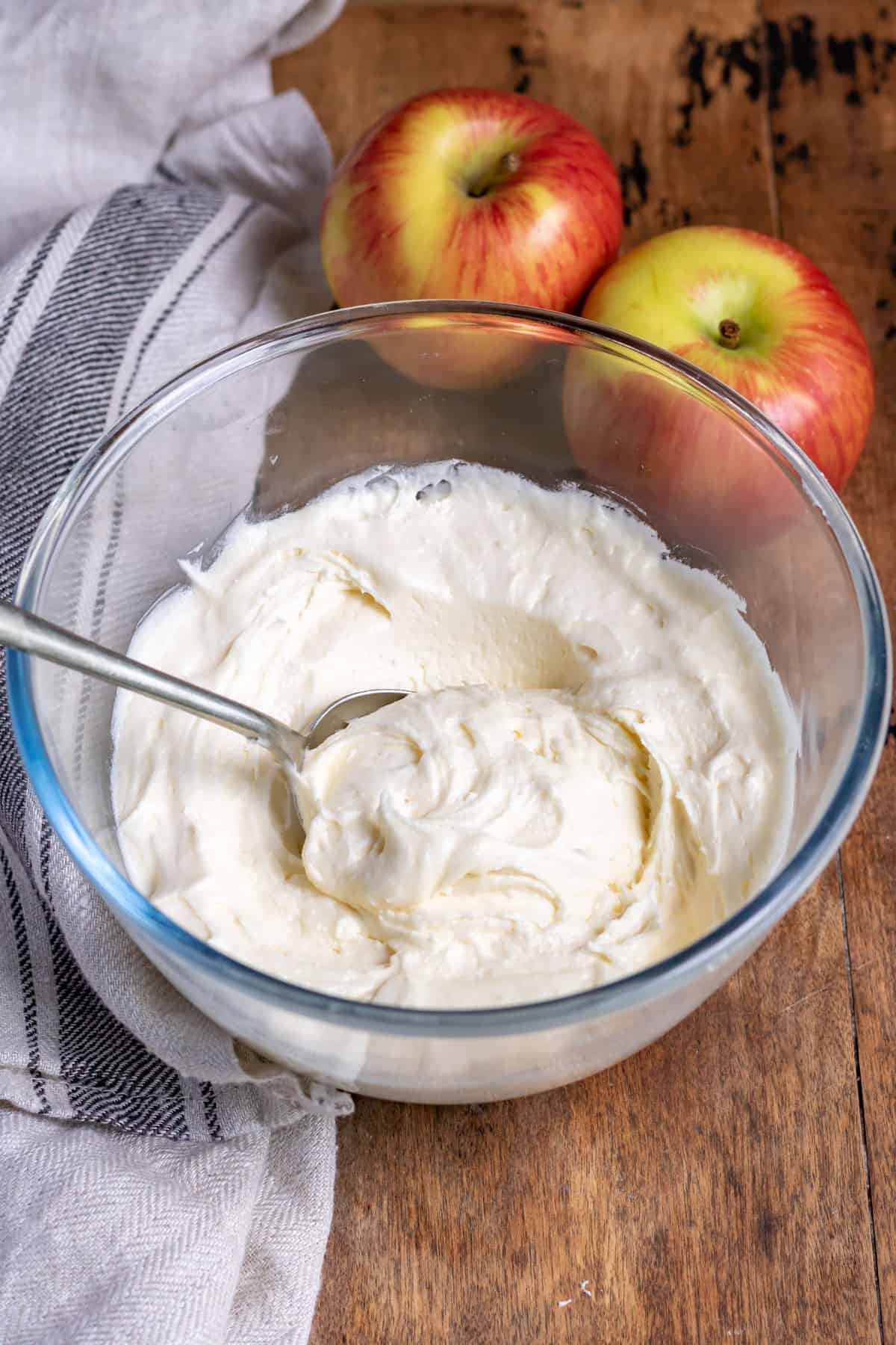 Bowl of apple frosting on a table, with a spoon in it.