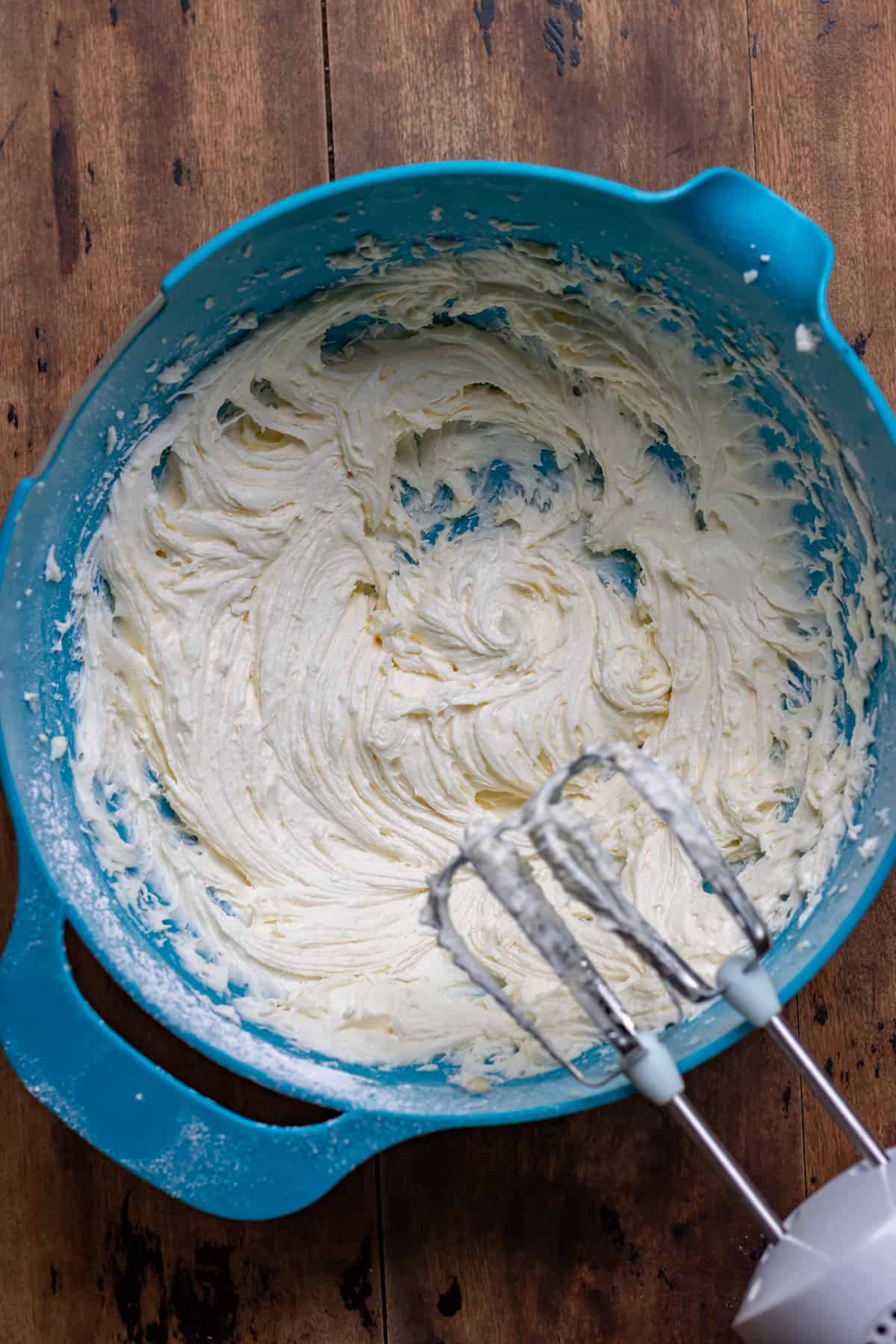 Beaten frosting in a bowl with electric mixers.