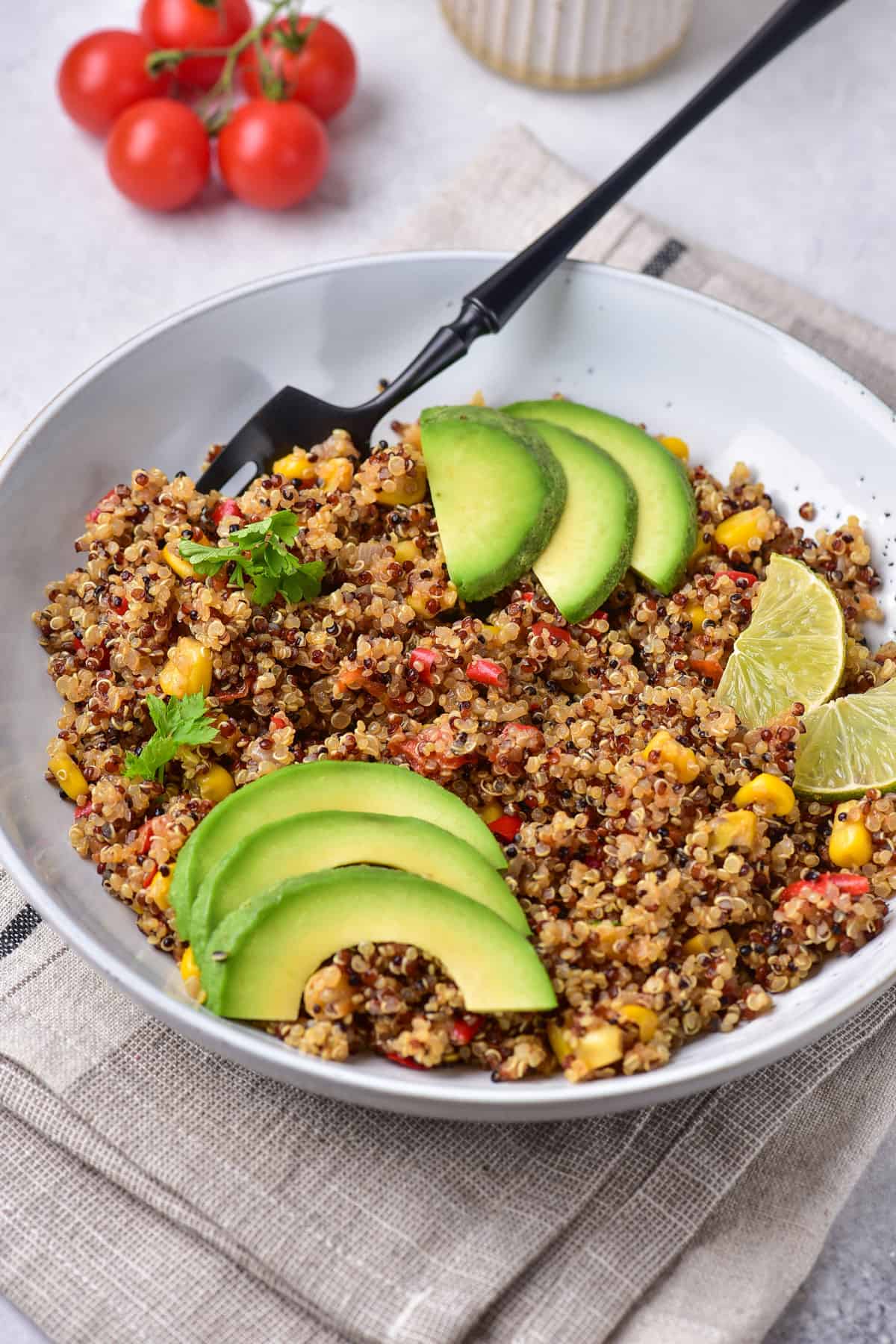 Table with a bowl of mexican quinoa salad topped with slices of avocado.
