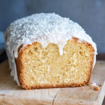 Close up of a coconut bread loaf with a slice cut out.