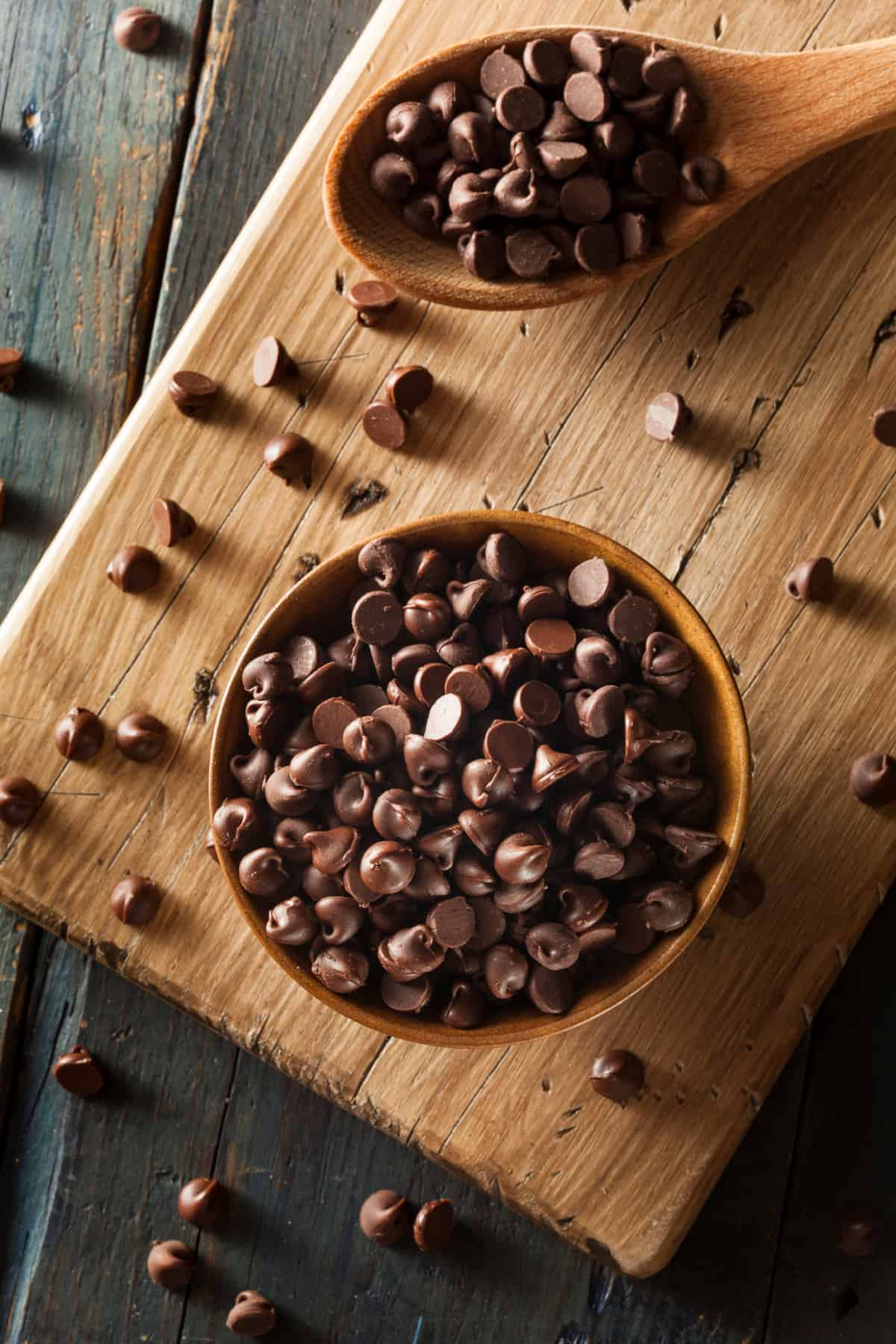 Bowl of chocolate chips on a wooden board.