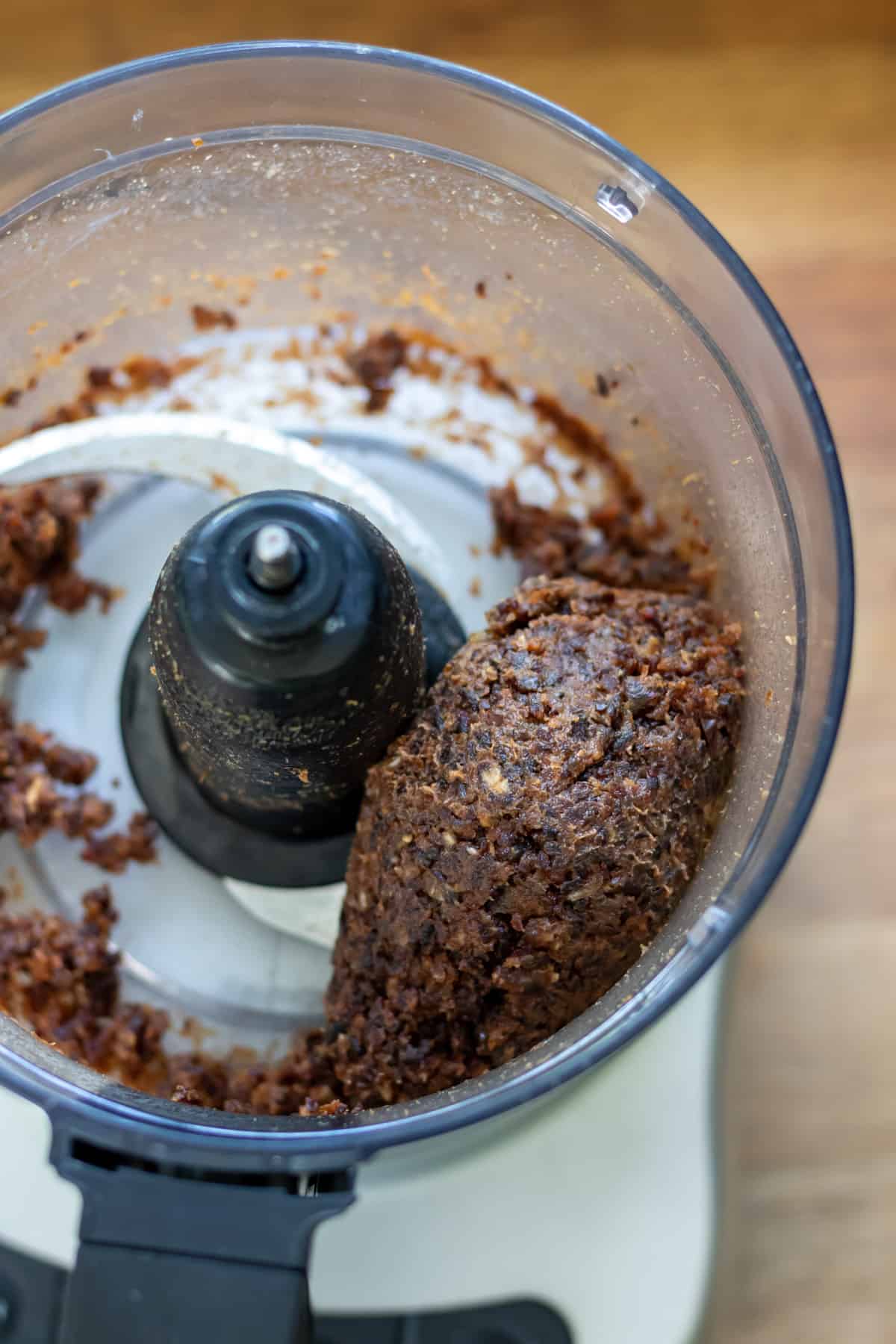Dates being pureed in a food processor until it forms a sticky ball.