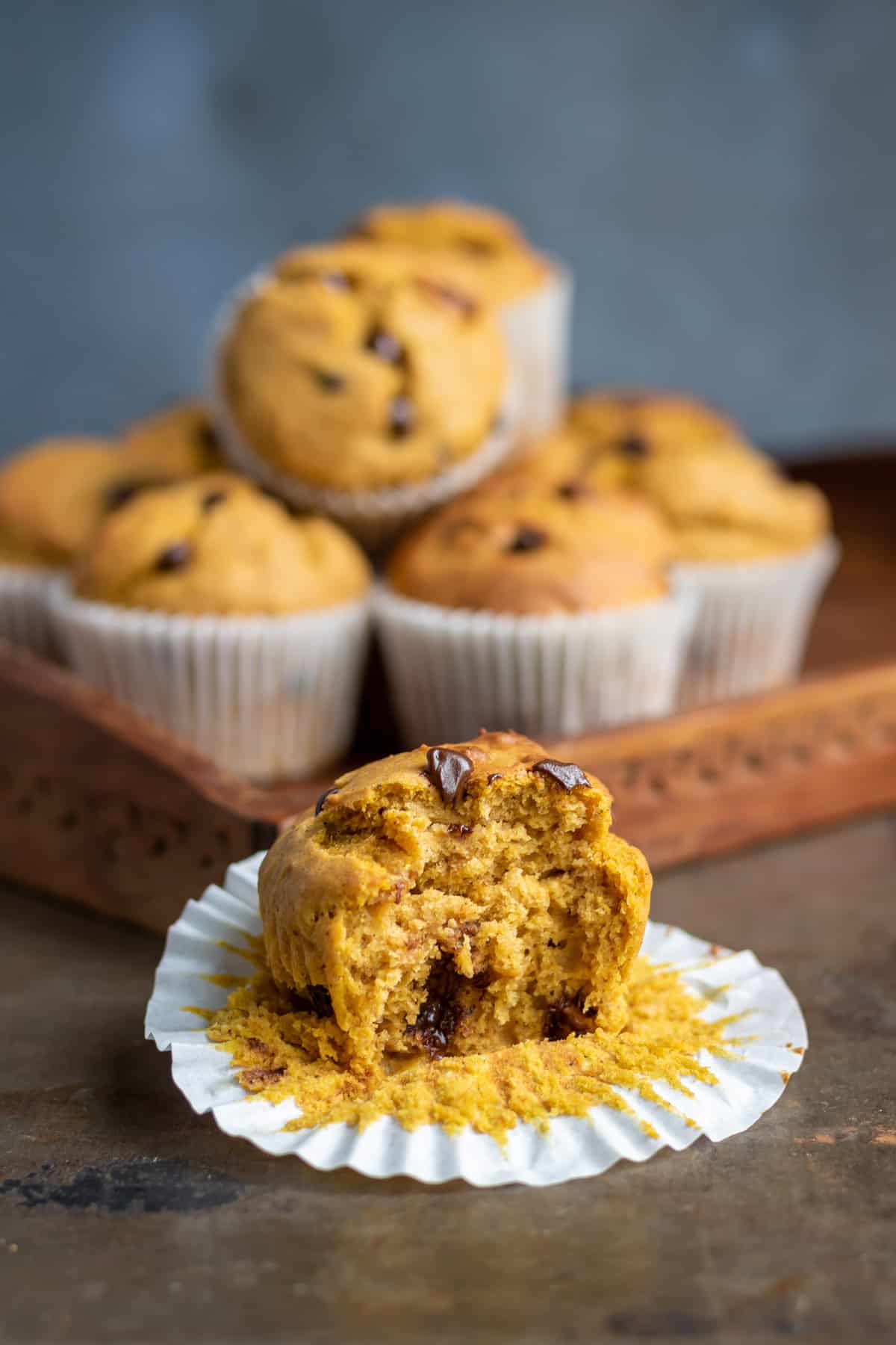 Muffin with a bite out, with a pile of muffins behind it.