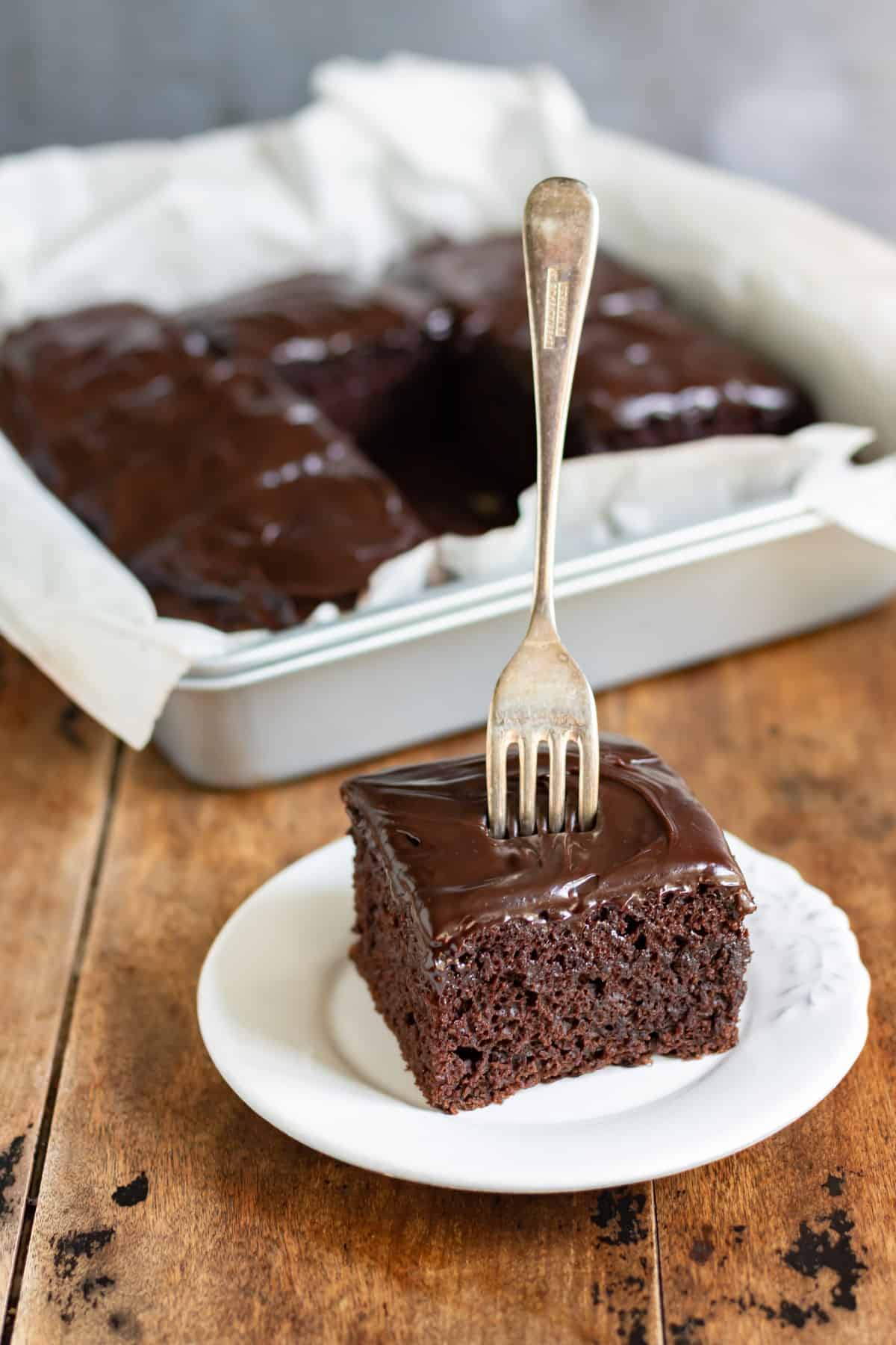 A fork sticking up in a square slice of chocolate crazy cake.