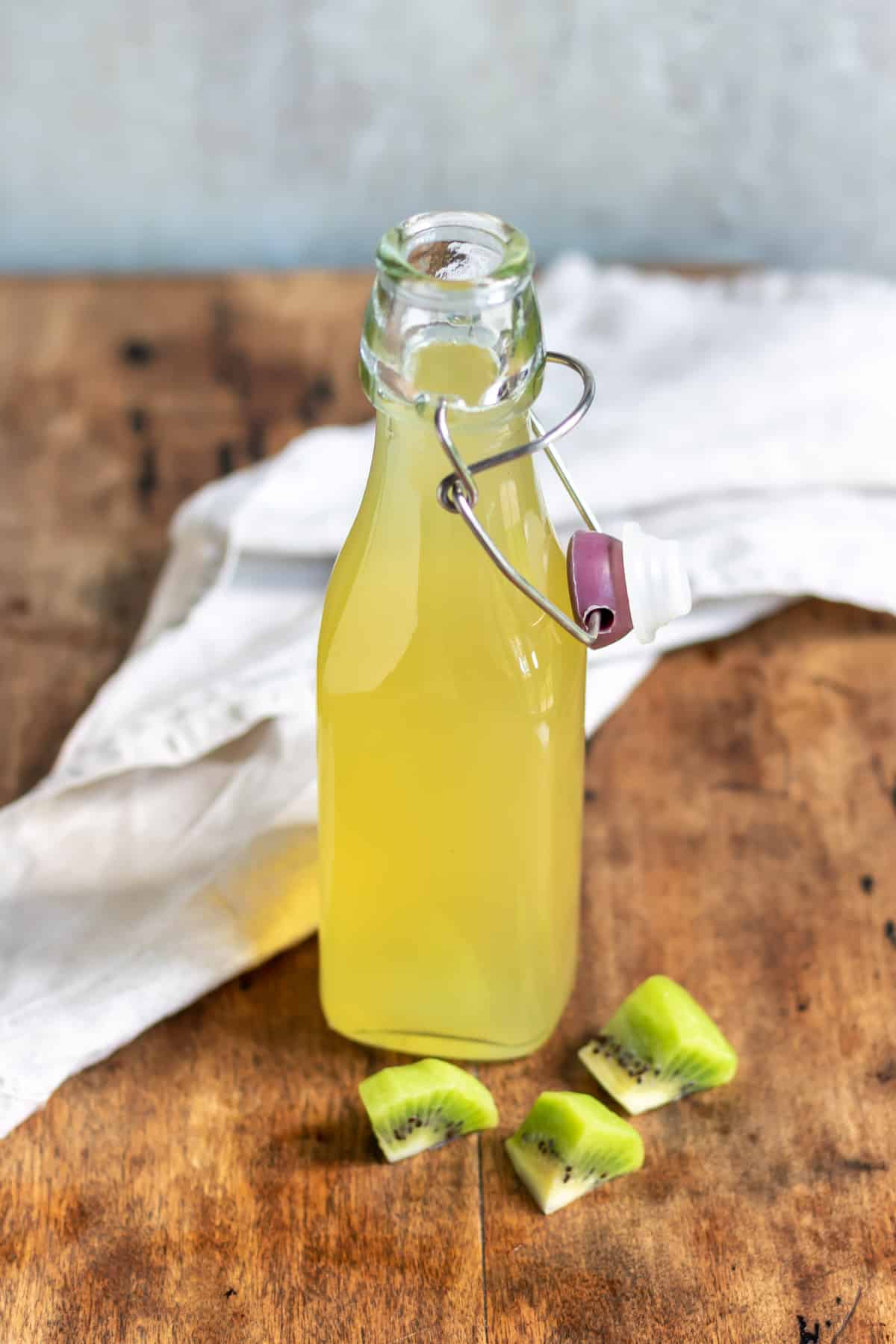 Wooden table with a bottle of kiwi syrup.