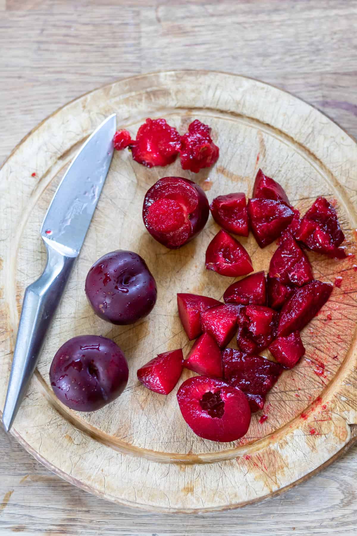 Cutting plums on a wooden board.