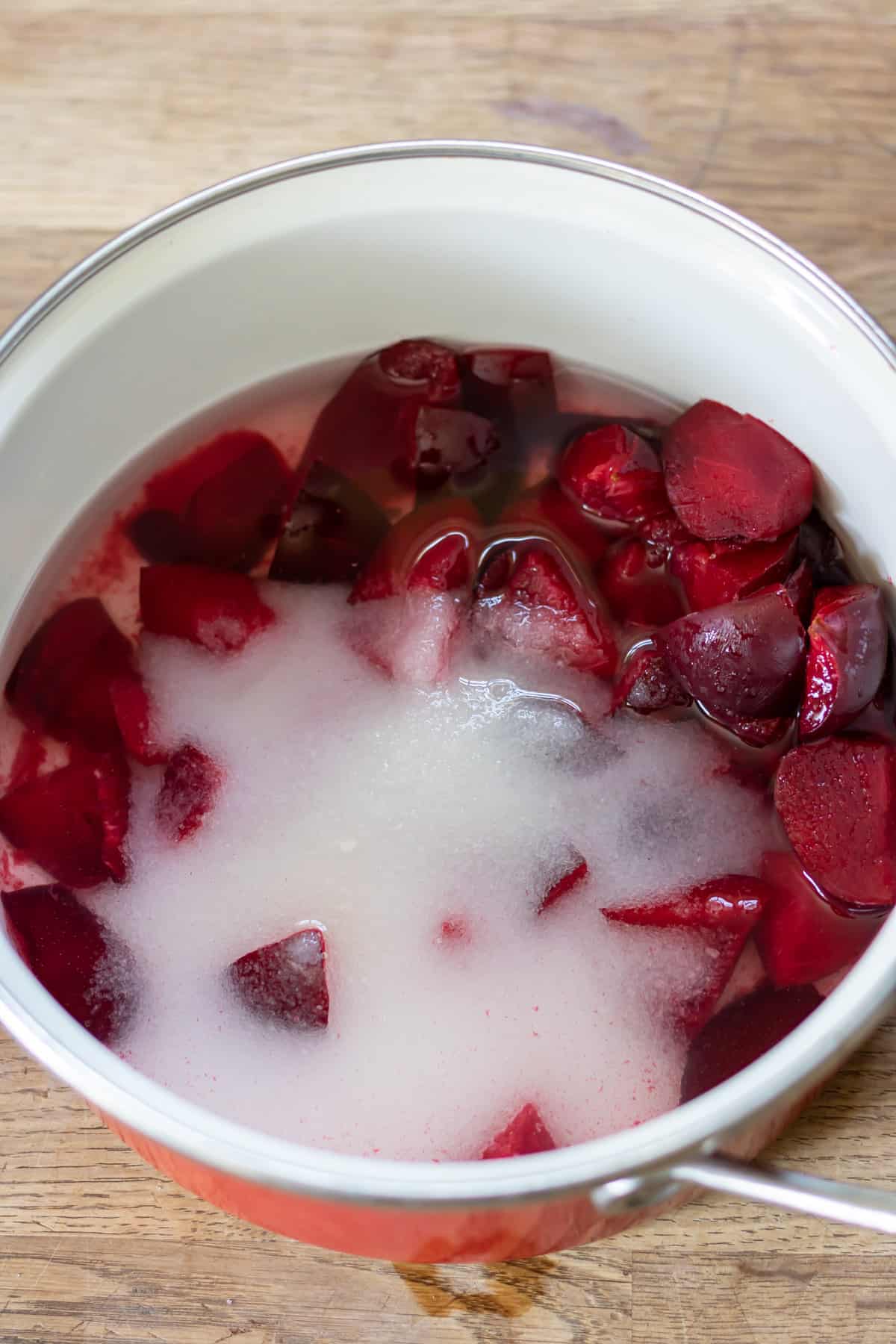 Chopped plums, sugar and water in a pot.