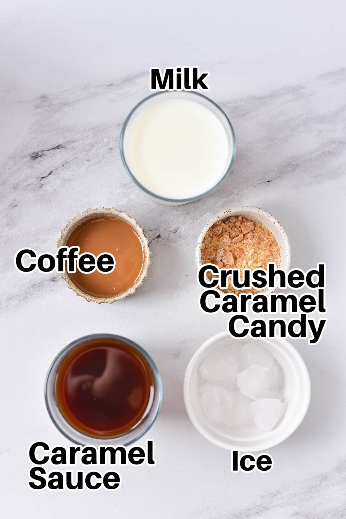 Ingredients on a table: milk, crushed caramels, coffee, caramel sauce and ice.
