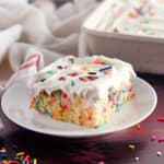 Side view of a square of wacky cake with vanilla frosting and funfetti.