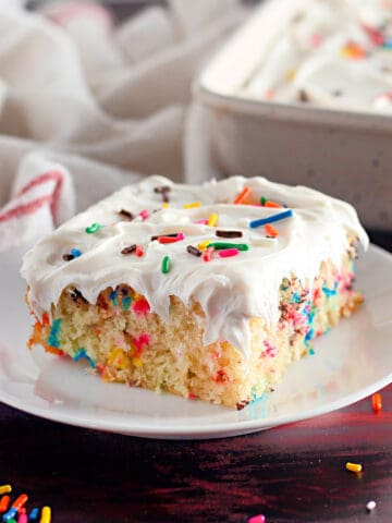 Side view of a square of wacky cake with vanilla frosting and funfetti.
