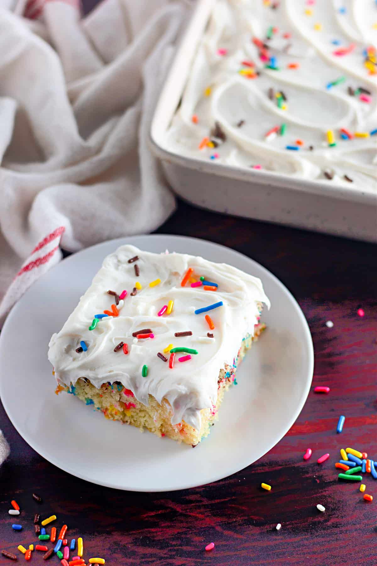 Slice of vanilla wacky cake on a plate, with frosting and funfetti.
