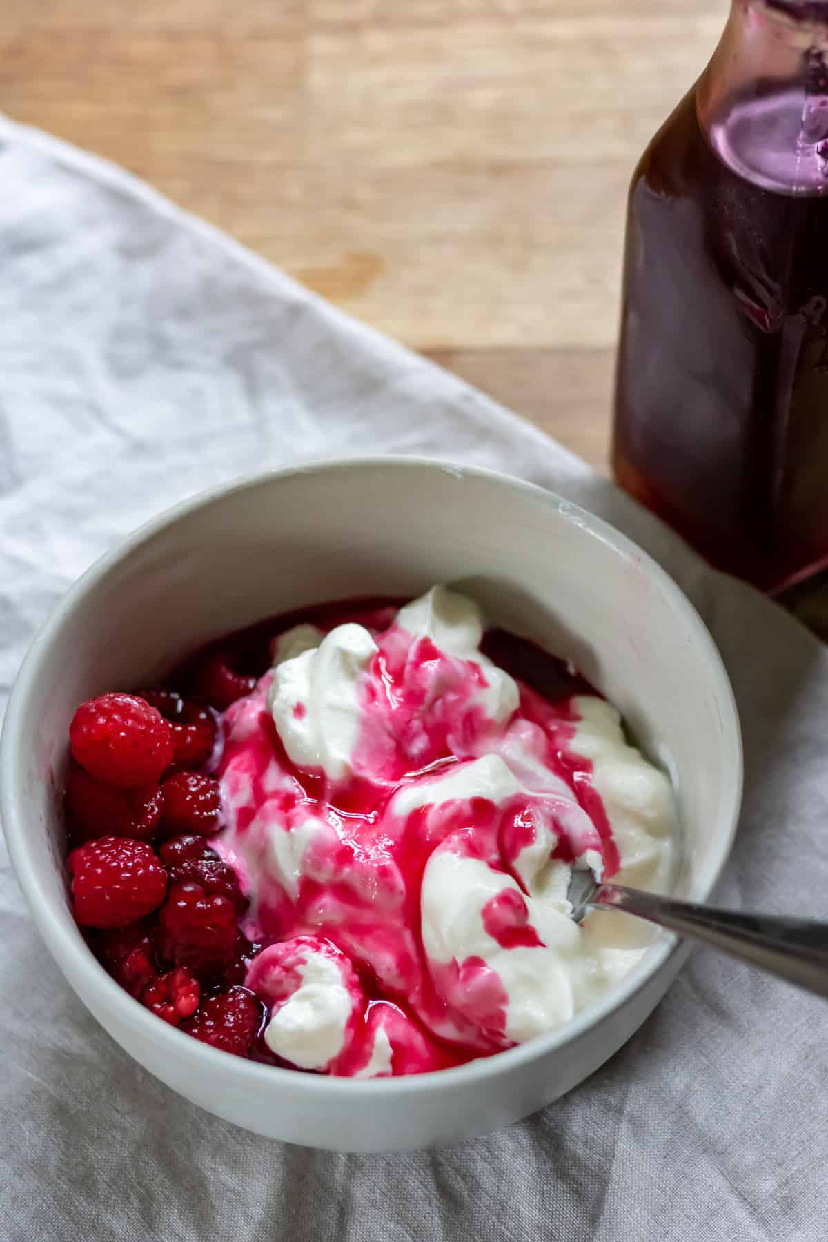 Bowl of yogurt and berries drizzled with blackcurrant simple syrup.