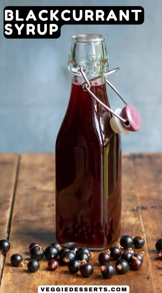 Bottle of simple syrup on a table with blackcurrants next to it, with text: Blackcurrant Syrup.