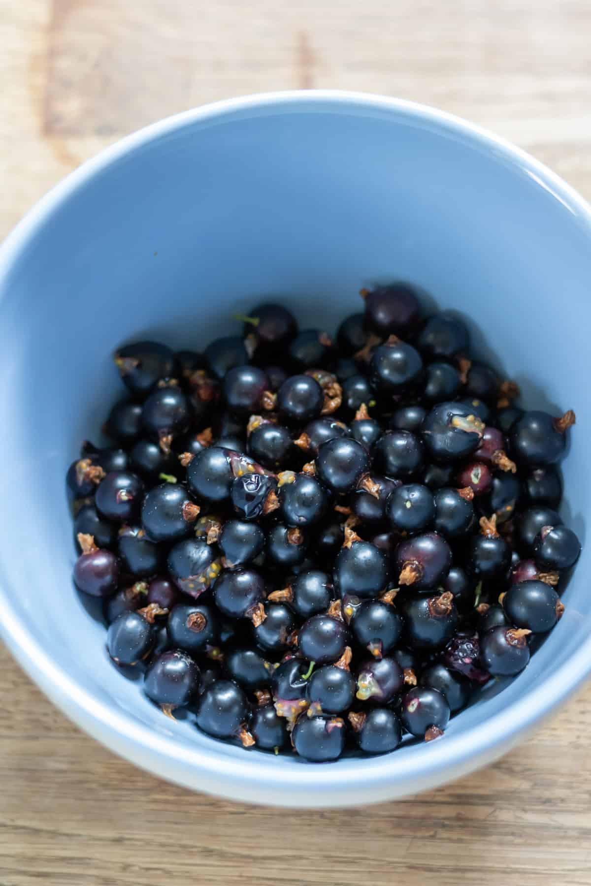 Bowl of rinsed fresh blackcurrants.